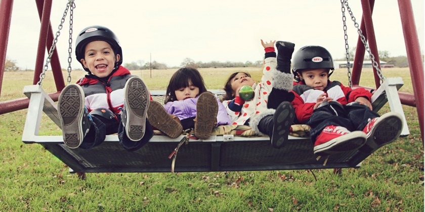 Four adopted children play on a porch swing.