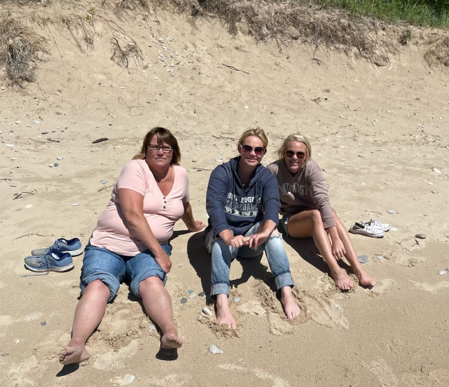 Mandy's mom, sister, and Mandy sitting on the beach soaking in the Michigan sun. 
