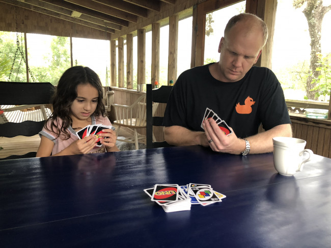 Playing Uno on front porch of a cabin we were staying at when we took the girls to float the river and go to their first concert.