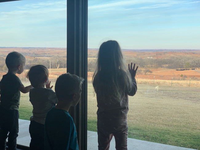 Kids watching their Papa feed the cows in the valley.